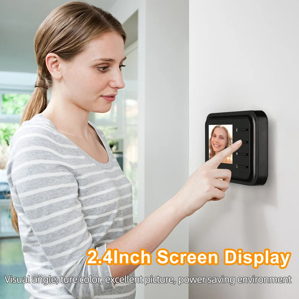 A woman using a compact black 2.4-inch digital door peephole monitor mounted on a white wall.