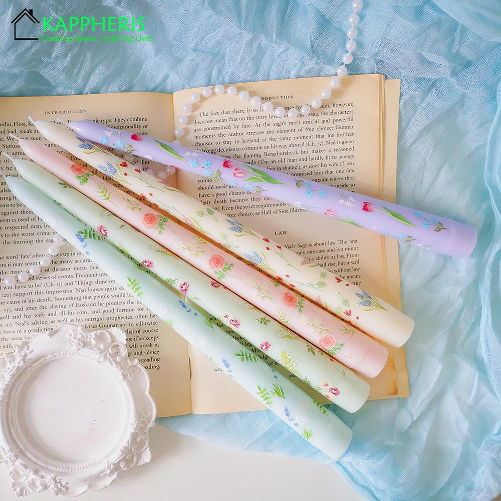 Set of four tapered dinner candles in pastel shades featuring delicate hand-painted floral patterns.