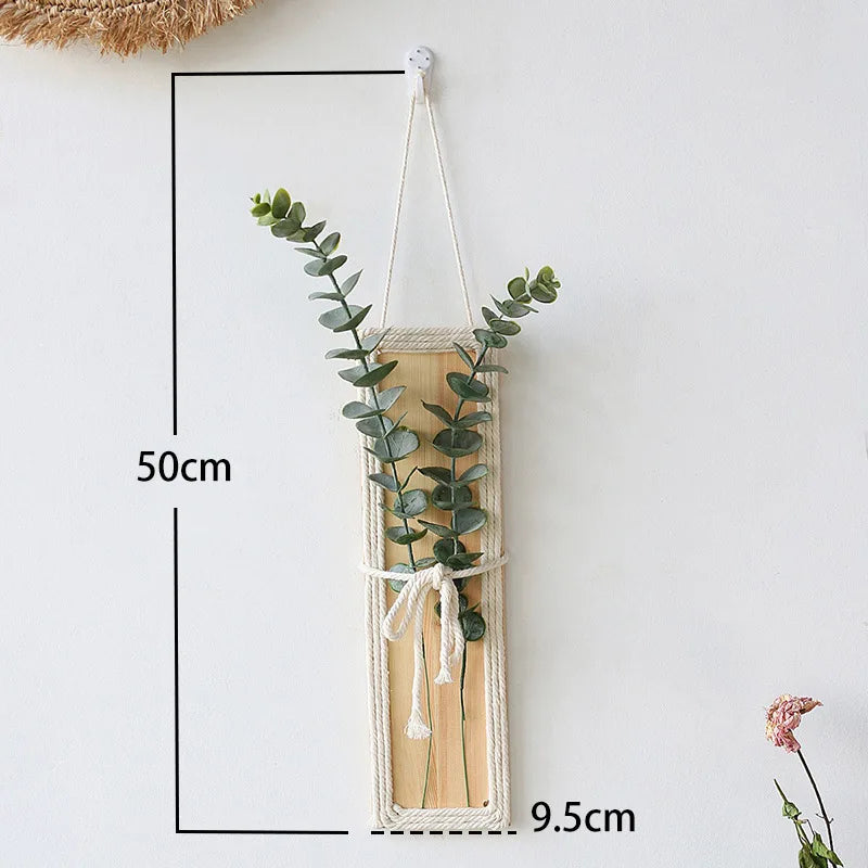 Bohemian wall hanging featuring a natural wood panel wrapped in cream rope with two stems of artificial eucalyptus.