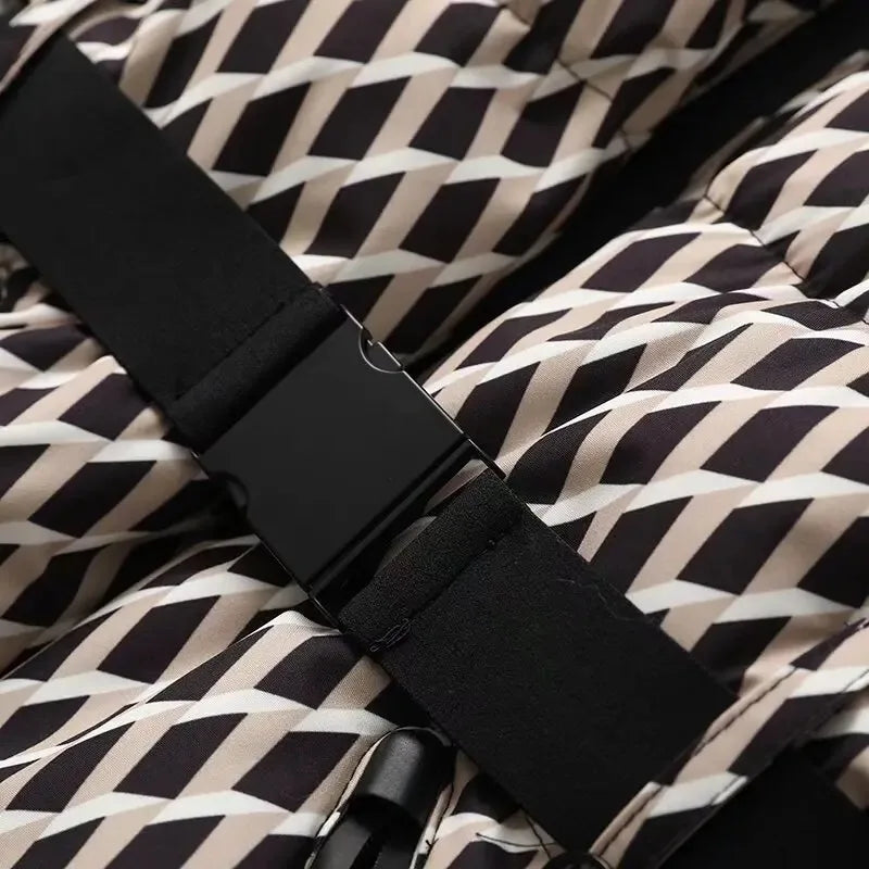 Quilted jacket in a geometric black, white, and beige print featuring a black adjustable strap with a buckle.
