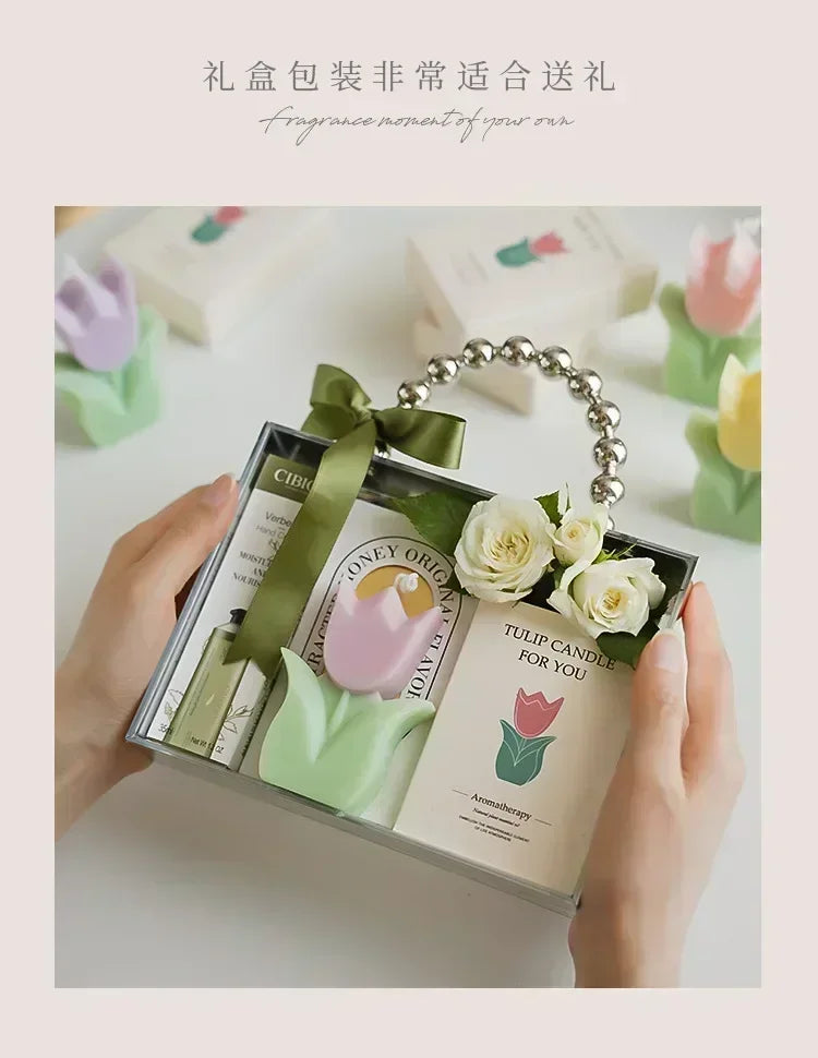 Gift set in a clear box with pearl handle, featuring a tulip-shaped candle, hand cream, and decorative white roses.