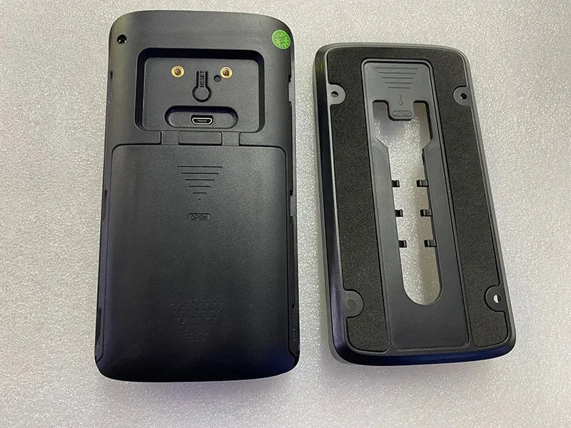 The back view of a black wireless video doorbell with a charging port and its rectangular mounting bracket.