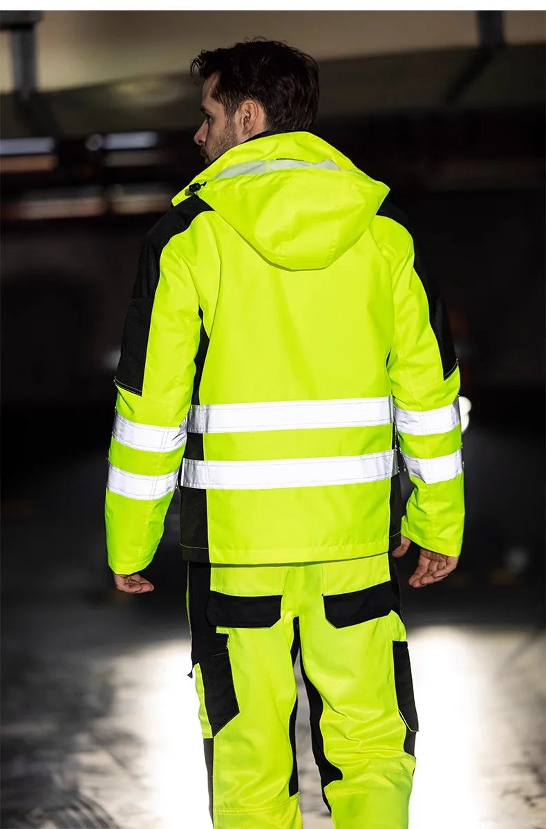A man wearing a neon yellow and black waterproof hi-vis work jacket with reflective strips and matching trousers.