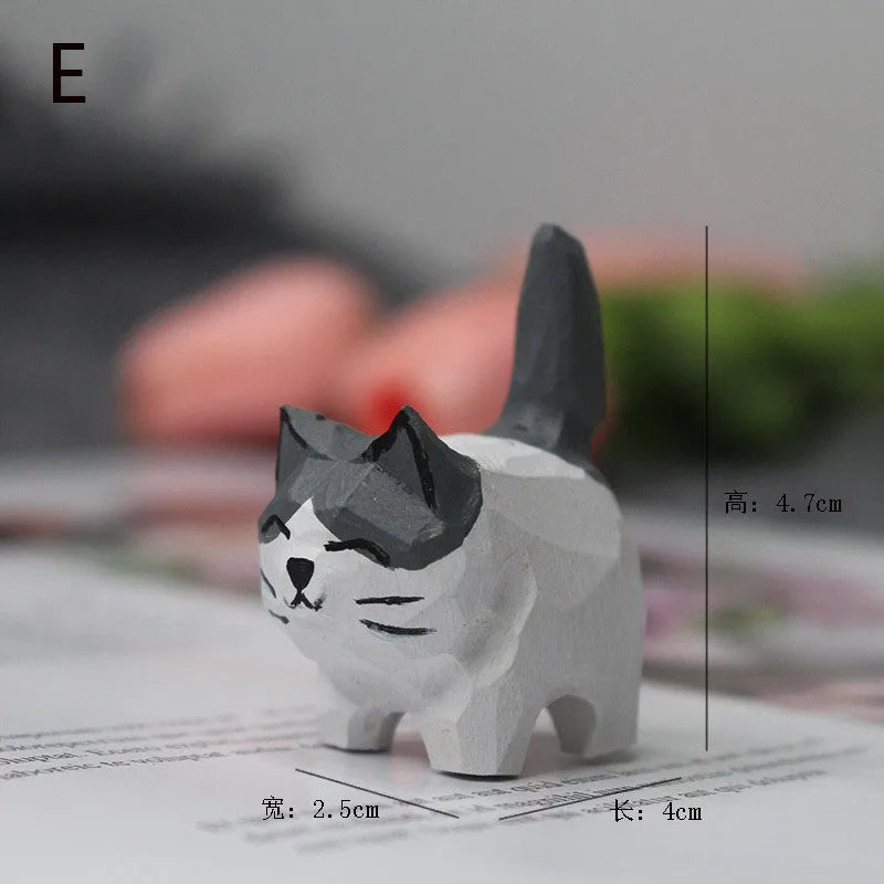 Small, hand-carved grey and white wooden cat figurine with a geometric, faceted design.