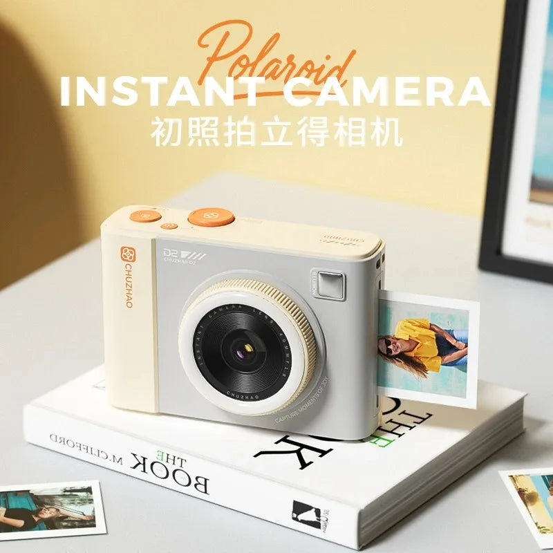 Cream and grey plastic instant camera with orange buttons and a small photo printing from the side.