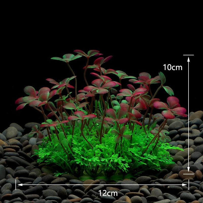Artificial aquarium plant with red-tipped clover-like leaves and bright green fern-like base on black gravel.