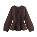 Dark brown long-sleeve wrap jacket with a V-neck, flared peplum hem, and a thin tie-waist belt.
