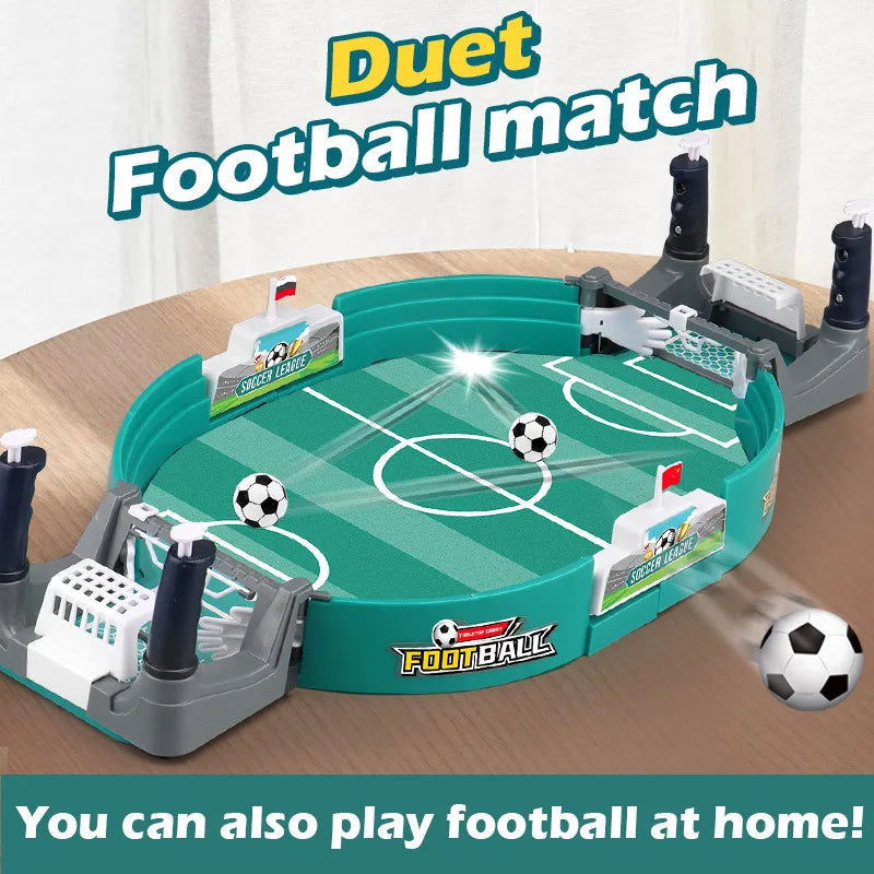 Tabletop football game with a green pitch, white goals, and two small black and white soccer balls on a wooden surface.