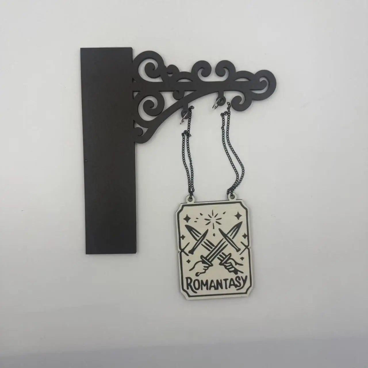 Black wall-mounted bracket with a hanging rectangular wooden sign featuring a sword illustration and 'ROMANTASY' text.