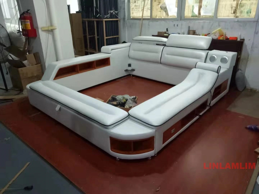 Modern white leather platform bed with integrated storage shelves, headrest and built-in bedside speakers.