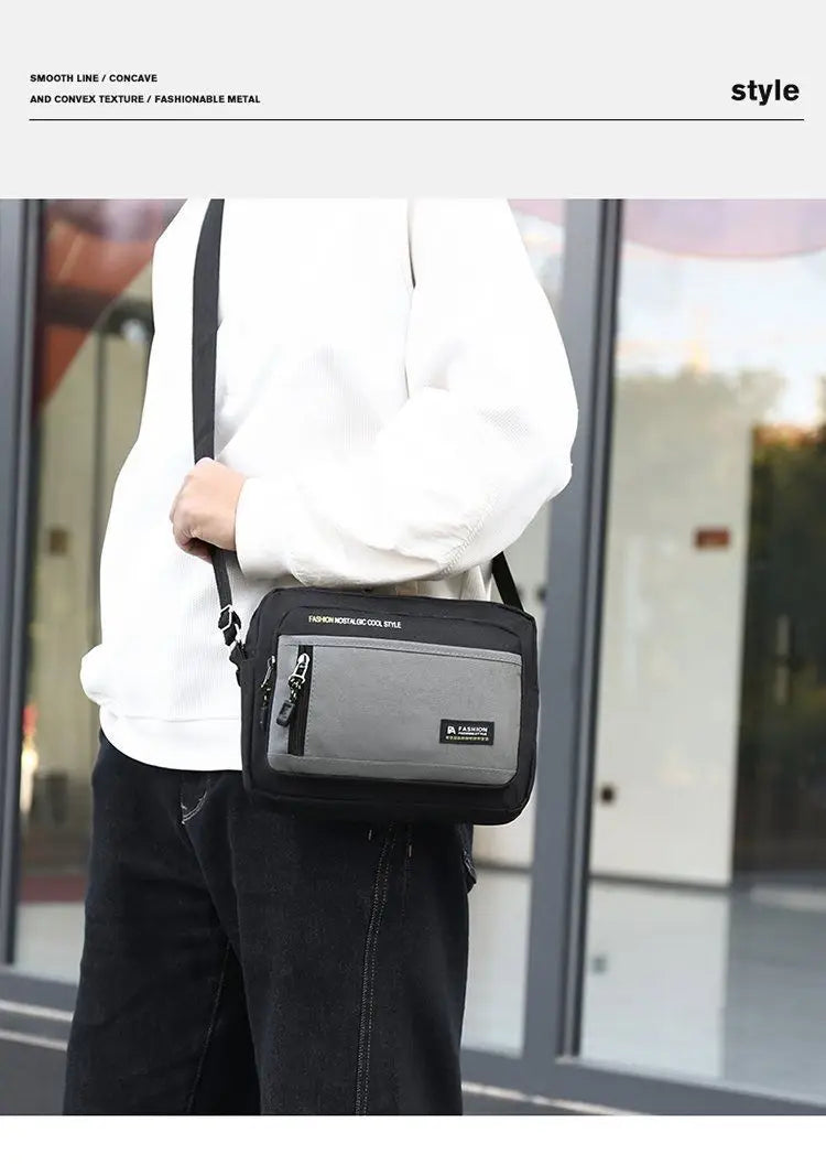 A person wearing a black and grey rectangular crossbody shoulder bag with a zipped front pocket and adjustable strap.