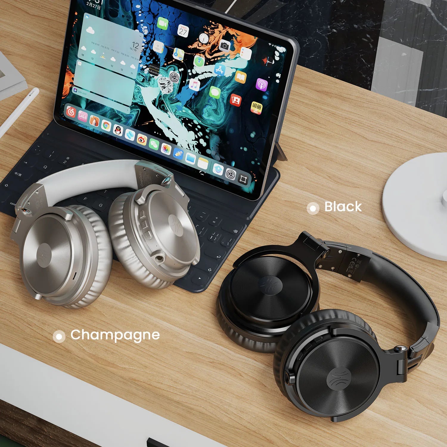 Champagne and black wireless over-ear headphones with microphone, displayed on a desk next to a tablet.