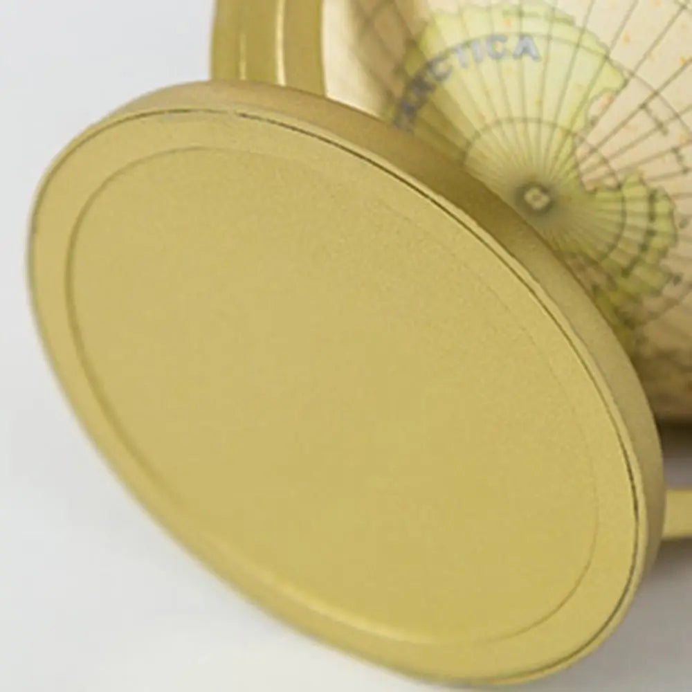 Close-up of a desktop globe with a smooth, matte gold circular base and a vintage-style map finish.
