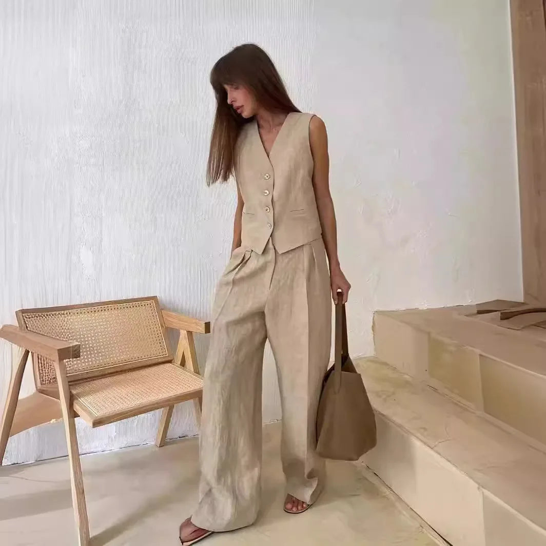 Beige linen-blend sleeveless button-down waistcoat and matching wide-leg trousers, styled with a brown tote bag.