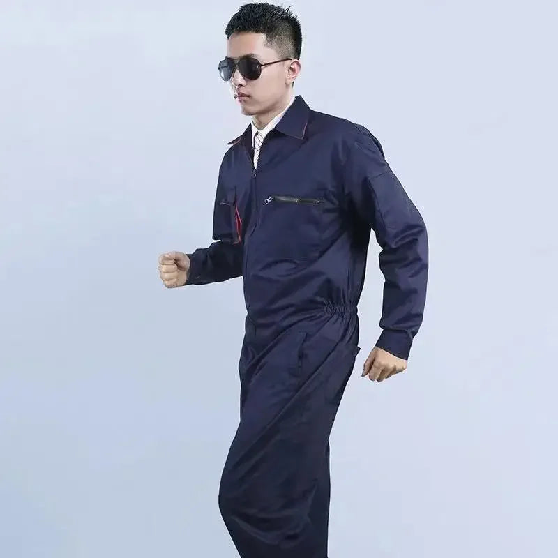 A man wears a dark blue long-sleeved work coverall with a zip-up front, collar, and chest pockets.
