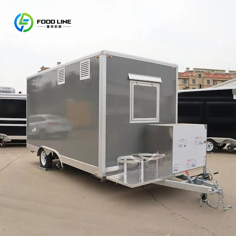 Gray mobile food trailer with a service window, metal vents, and a tow hitch on the front.
