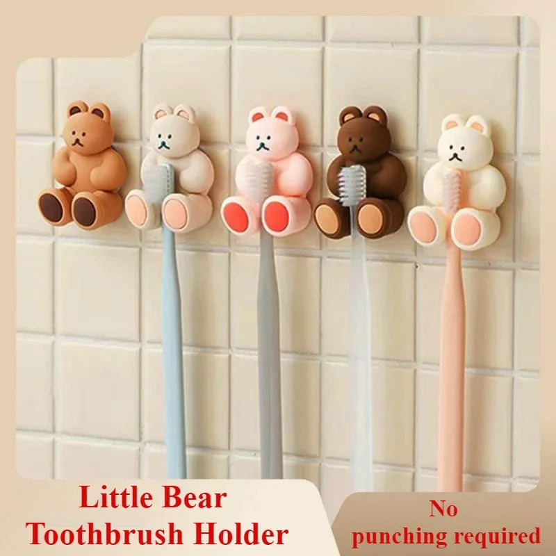 Five colourful little bear-shaped toothbrush holders mounted on a tiled bathroom wall.