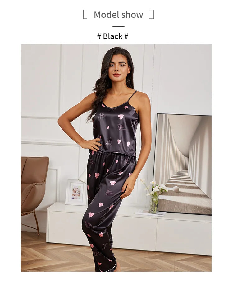 Black satin pajama set featuring a camisole top and trousers with pink heart and white squiggle patterns.