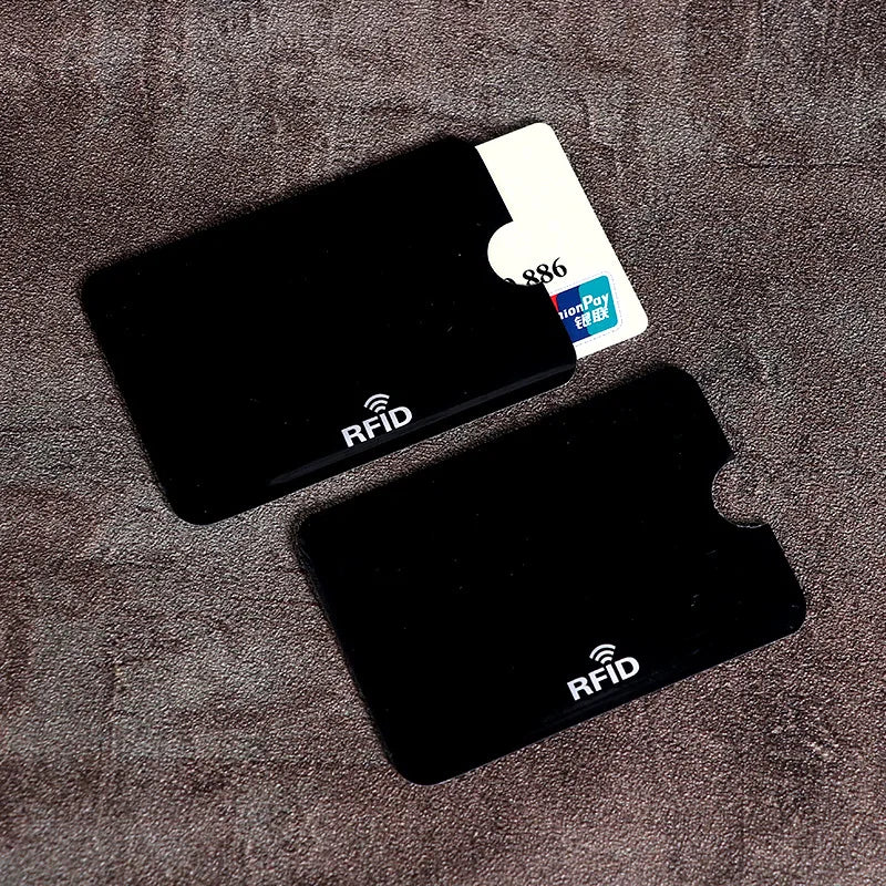 Two black, thin plastic RFID-blocking sleeves with thumb cutouts, one containing a credit card.