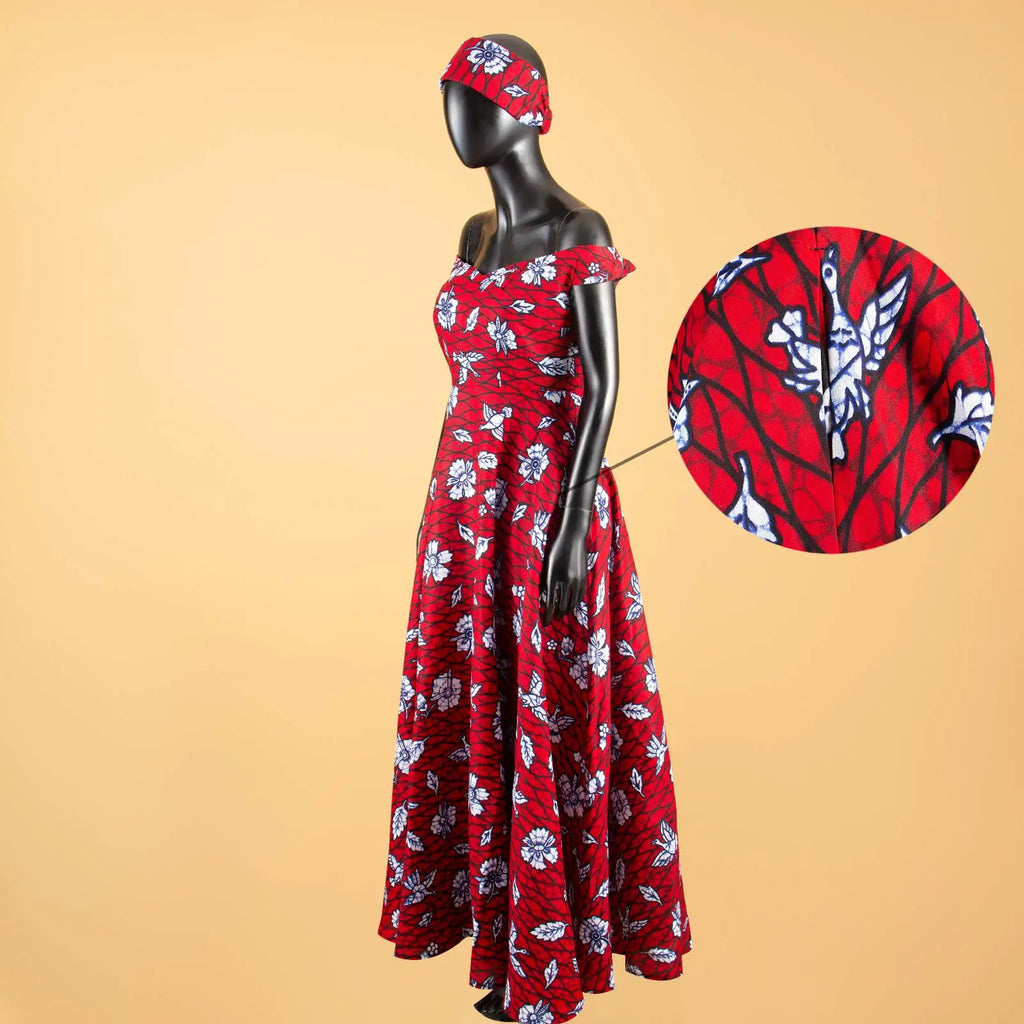 Red off-shoulder maxi dress with a white floral and bird print, featuring a matching headband on a black mannequin.