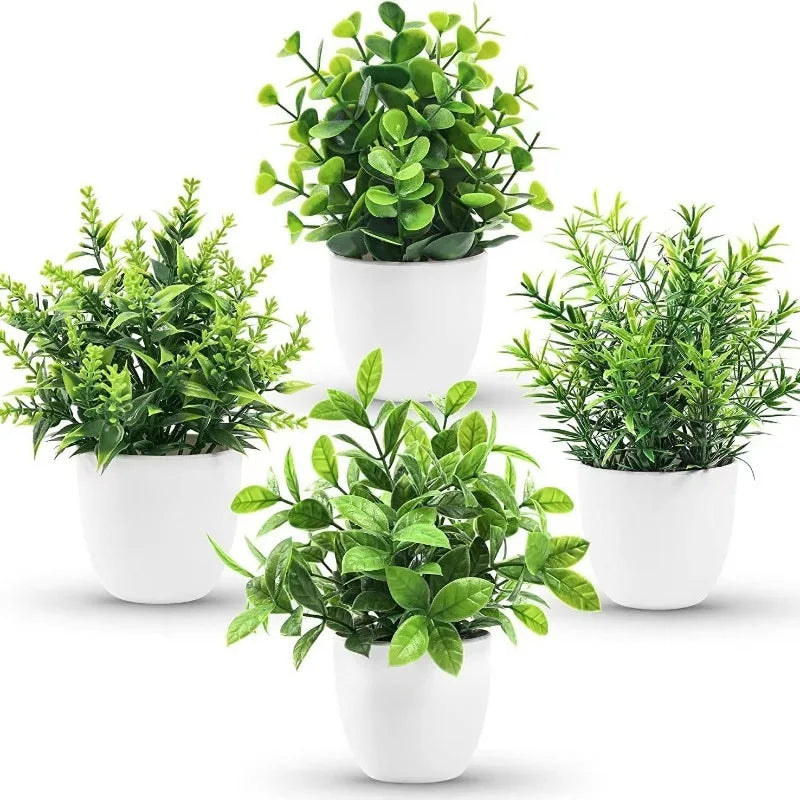 Four small artificial green plants with varied leaf shapes, each in a simple white pot against a white background.