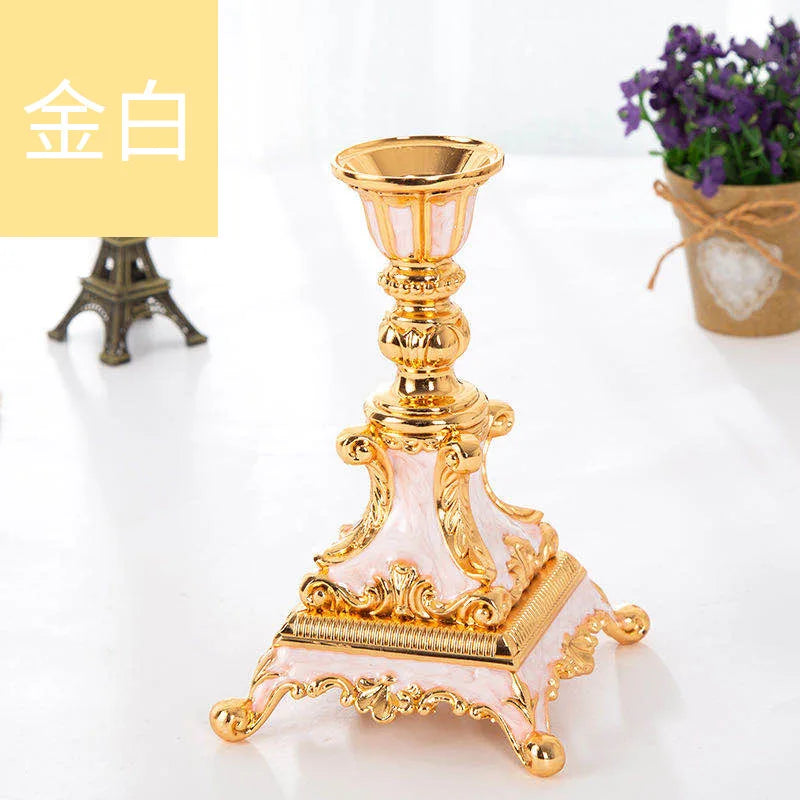 Gold and pink metal candle holder with ornate flourishes and a wide, footed base.