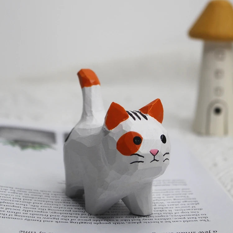 Small, hand-carved wooden cat figurine in white with orange patches, pointed ears, and a standing tail.