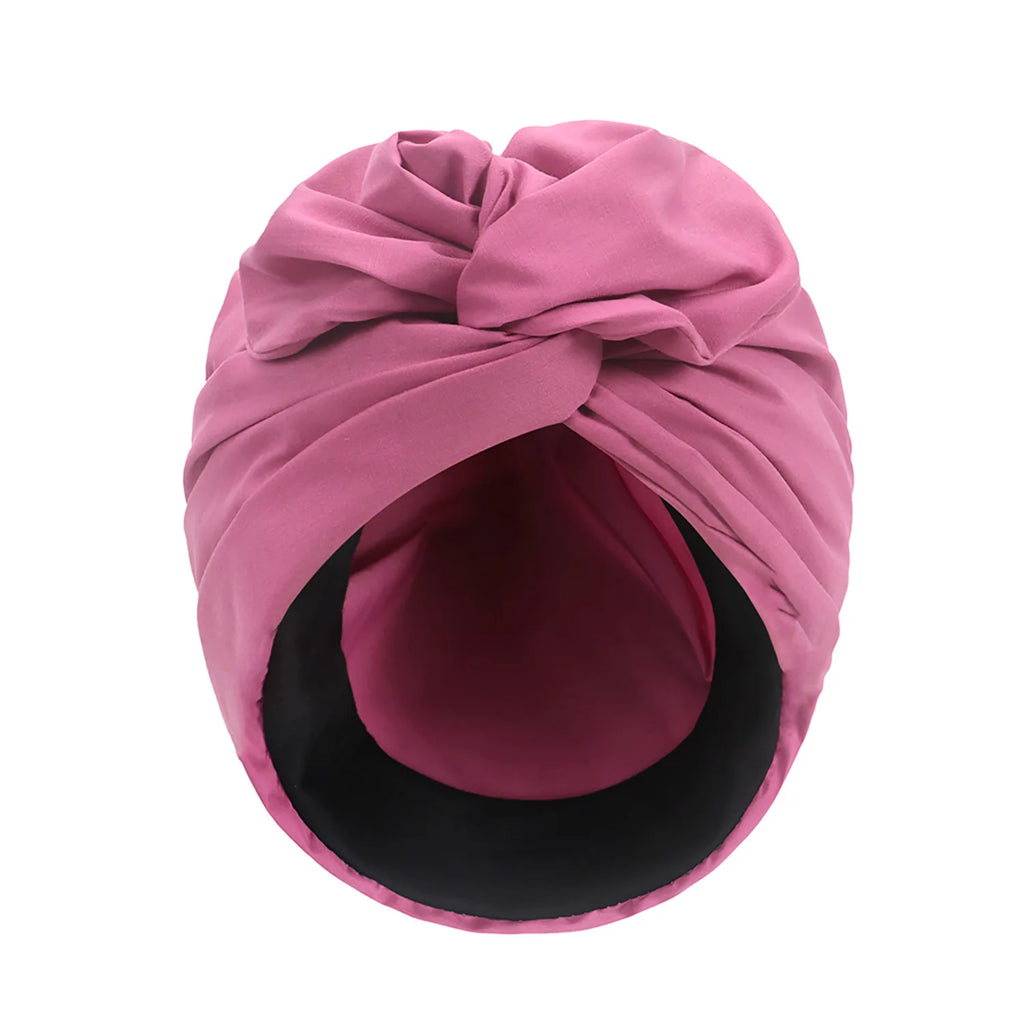 Dusty pink vintage-style turban hat with a decorative front knot and a smooth black inner lining.