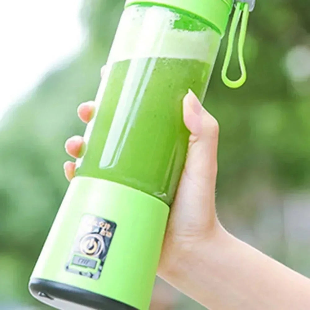 A person holds a bright green, portable, rechargeable smoothie blender filled with a green drink.