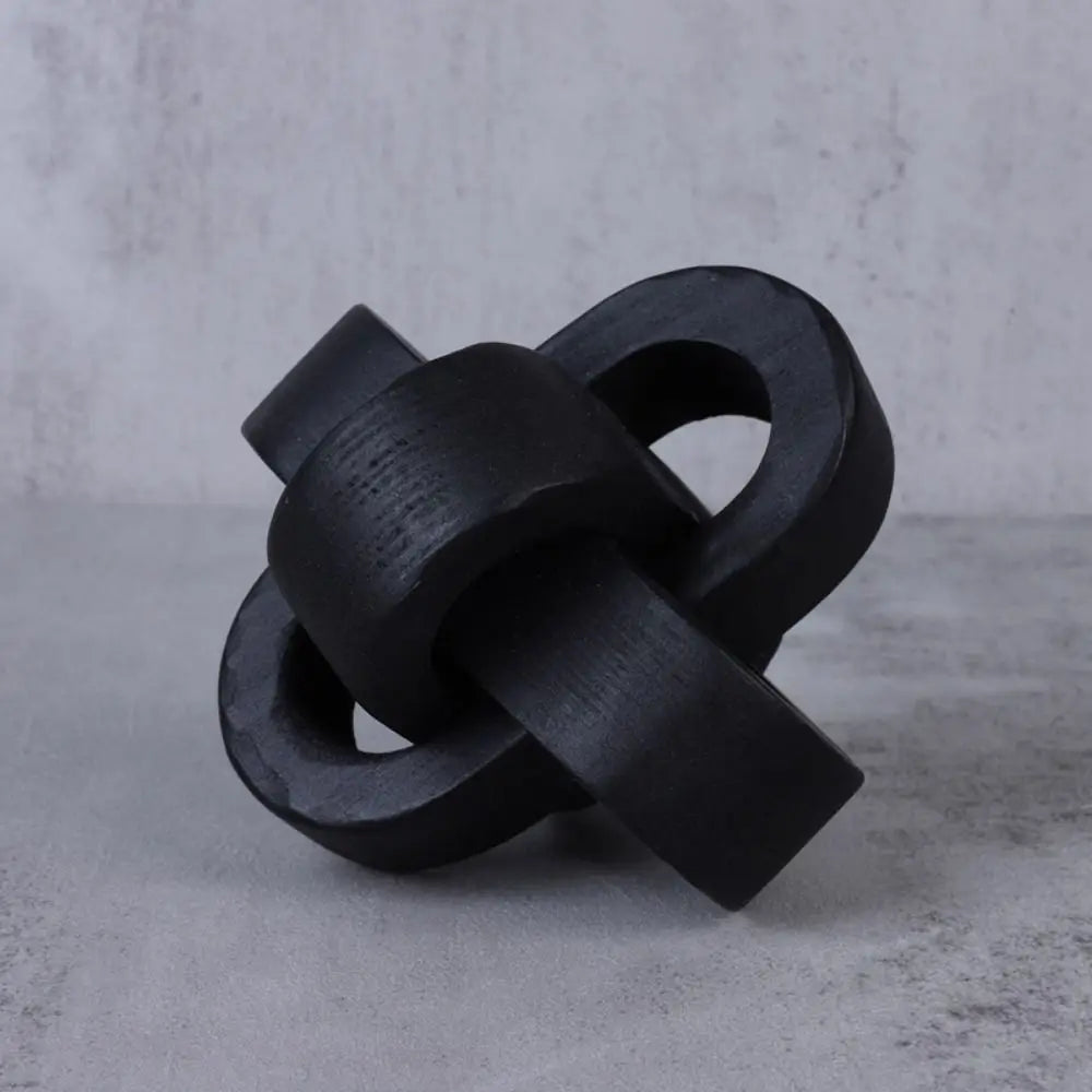 Modern decorative black wooden chain-link knot ornament with a rustic, textured finish.
