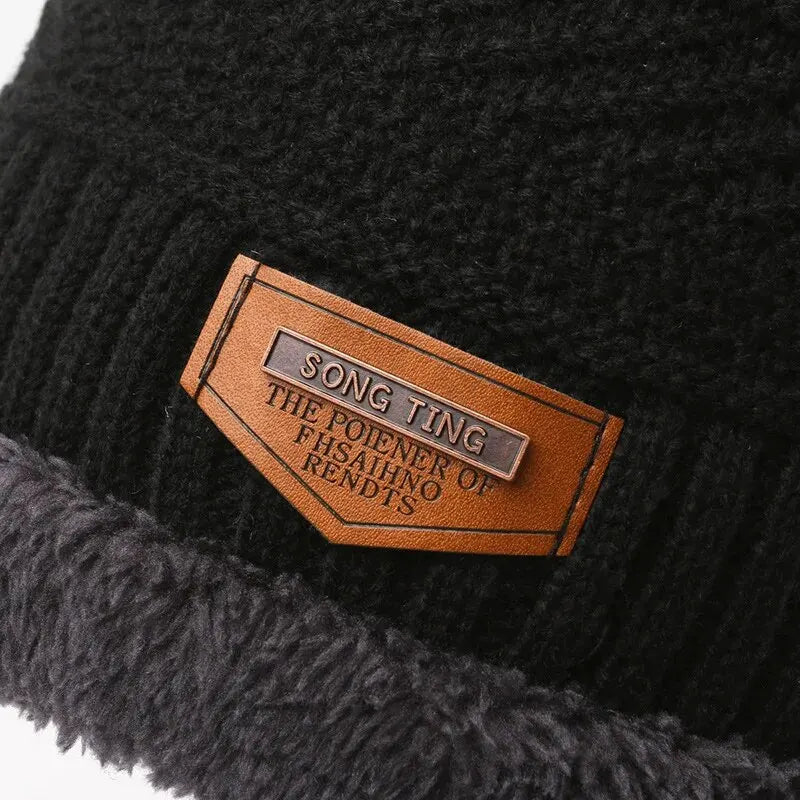 Close-up of a black, ribbed-knit winter hat with a soft, plush fleece lining and a brown leather-look patch.