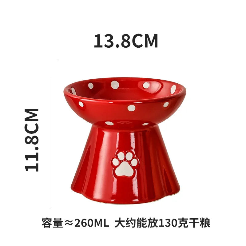 Red elevated ceramic cat bowl with white polka dots and a paw print design, measuring 13.8cm wide and 11.8cm high.
