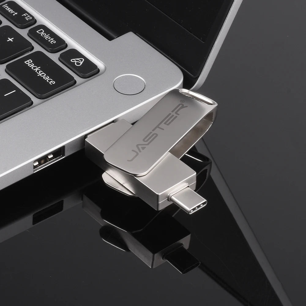 Silver dual-interface metal flash drive with USB-C and USB-A connectors plugged into a laptop.
