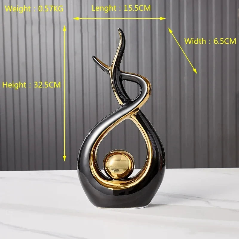 Abstract Nordic ceramic angel figurine in sleek glossy black and gold with a central sphere, set on a white surface.