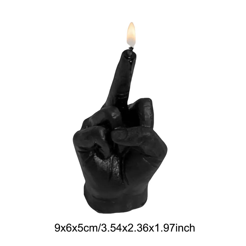 Black candle shaped like a hand giving the middle finger, with a lit wick on the raised finger. Measures 9x6x5cm.