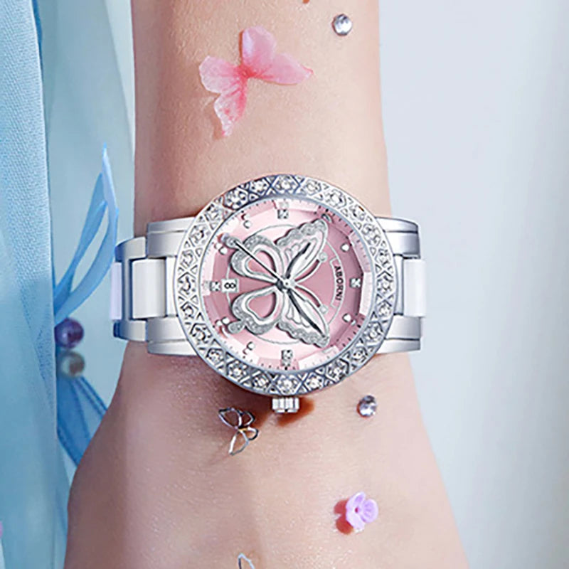 Luxury women's watch with a pink butterfly dial, crystal-encrusted bezel, and silver-tone strap.