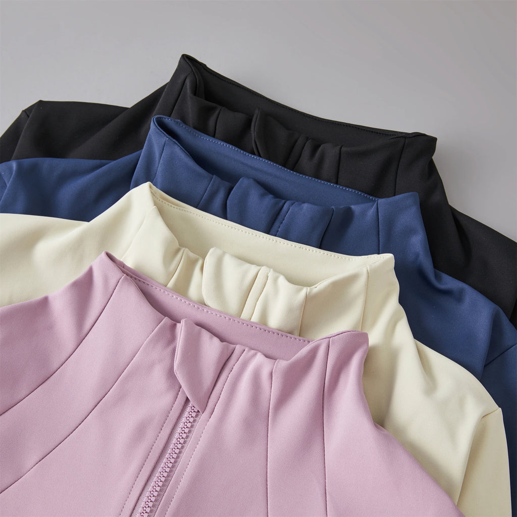 Stack of women's zip-up sports jackets in black, blue, cream, and mauve, featuring a high mock neck collar.