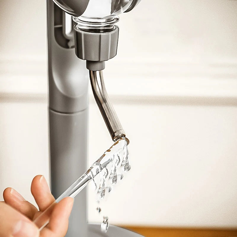 Grey hanging pet water dispenser with a metal nozzle releasing water, mounted on a stand.
