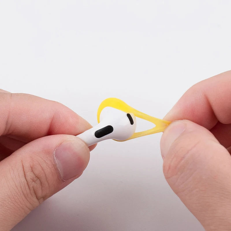 Bright yellow silicone ear hook accessory for AirPods Pro, shown being fitted to an earbud.