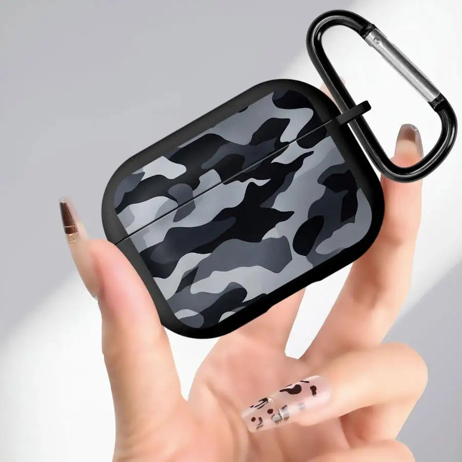 Grey camo silicone AirPods Pro case with black carabiner clip, held in a hand.