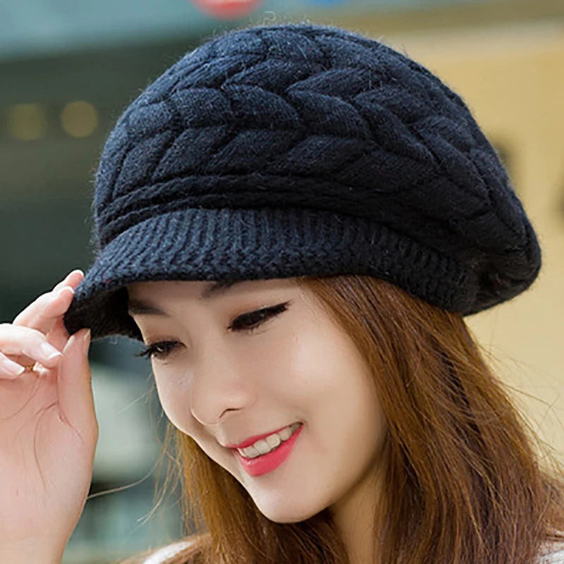 A woman wearing a cosy, dark navy blue knitted winter cap with a textured cable-knit pattern and a brim.