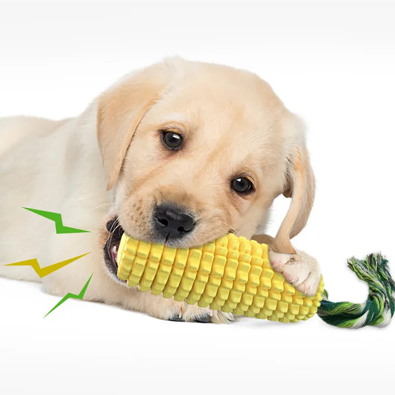 A yellow corn-shaped chew toy with a green rope tail being chewed by a golden puppy.