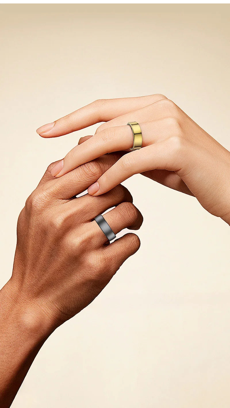 Two hands wearing sleek, minimalist smart health rings in polished gold and matte grey on a light beige background.