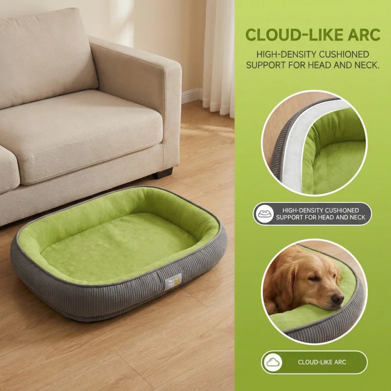 Rectangular green and grey pet bed with raised cushioned borders on a wooden floor near a beige sofa.