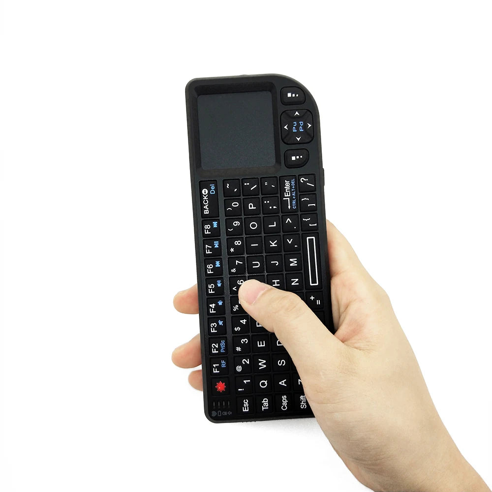 Black plastic handheld mini wireless keyboard with integrated touchpad and directional arrow keys held in a hand.