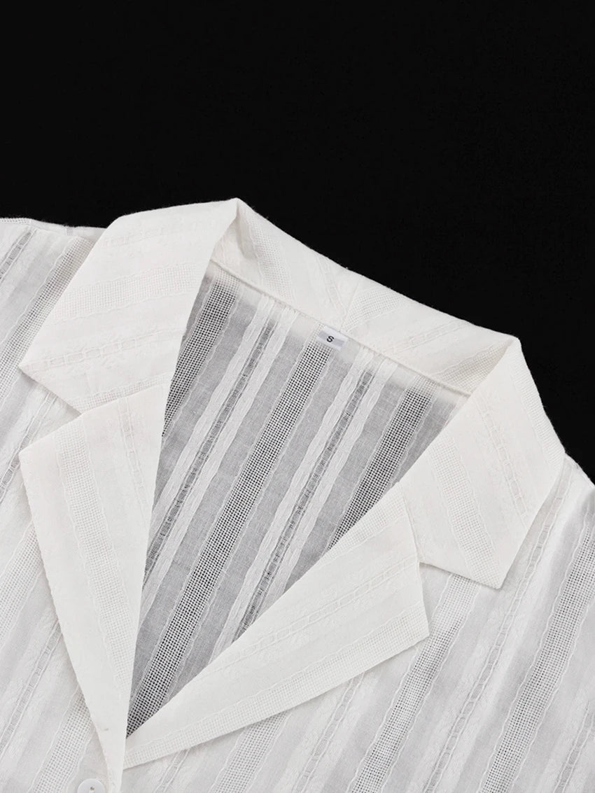 Close-up of a white, sheer collared shirt with a textured, vertical striped pattern.