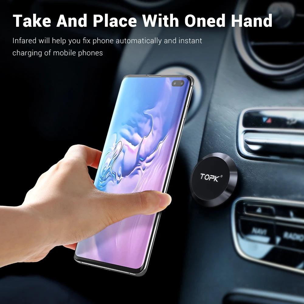 A round, black magnetic car phone mount attached to a vehicle dashboard, holding a smartphone.