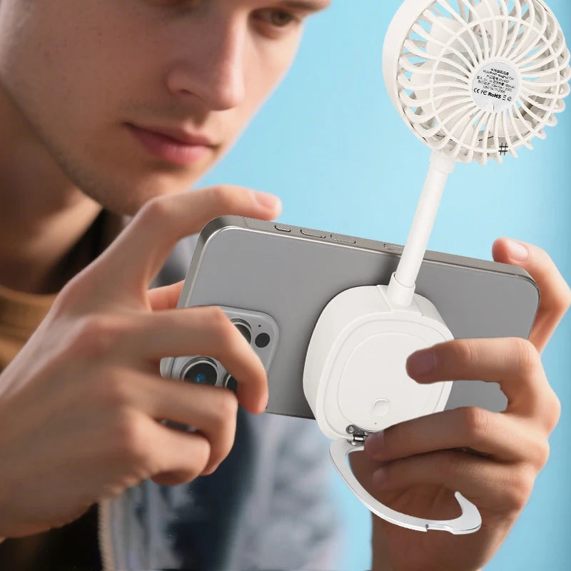 Portable white phone-mounted cooling fan with flexible neck and ring grip stand being used by a person.