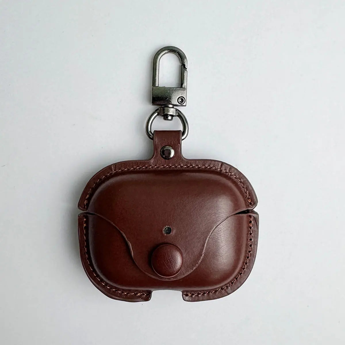 Brown leather AirPods Pro case with a press-stud closure and metal keyring clip, isolated on a white background.