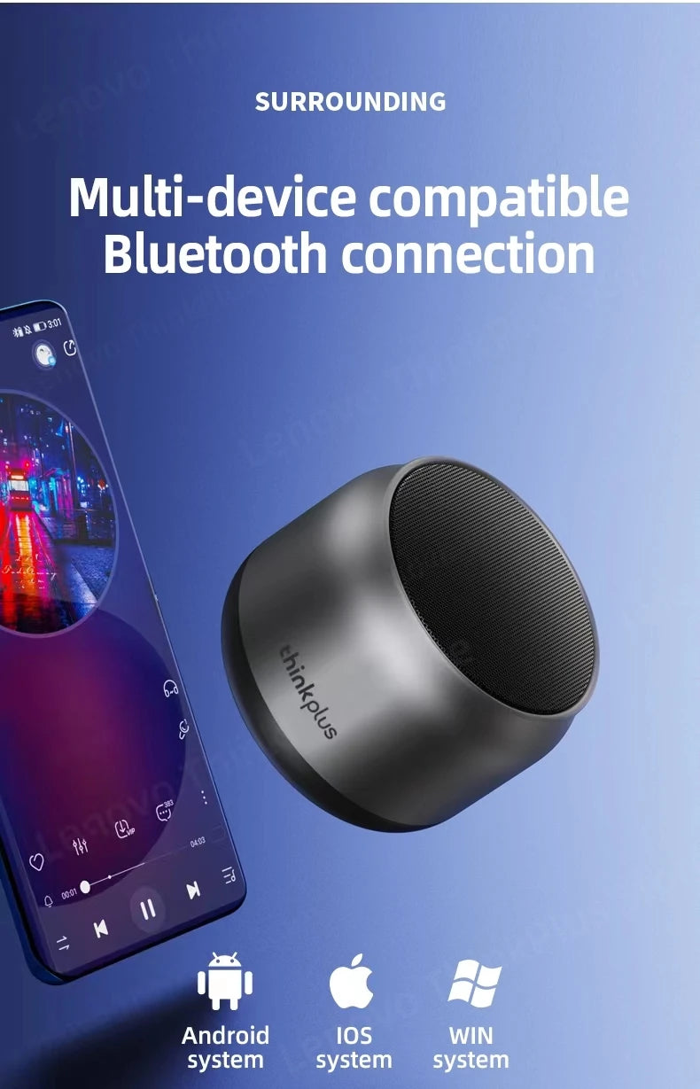 Small, sleek dark grey portable Bluetooth speaker next to a smartphone displaying a music app.